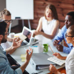 Team members engaged in a meeting around a table, actively discussing and listening to each other, representing strong group dynamics