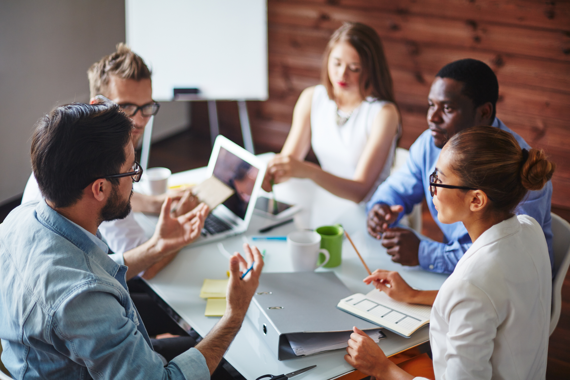 Team members engaged in a meeting around a table, actively discussing and listening to each other, representing strong group dynamics