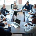 People gathered around a meeting table engaged in discussion, representing effective meeting processes on a high-performing team