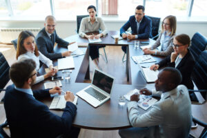 People gathered around a meeting table engaged in discussion, representing effective meeting processes on a high-performing team