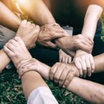 Hands of diverse individuals joining together in unison, symbolizing teamwork, unity, and inclusion.