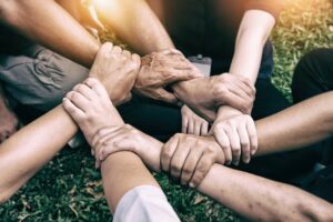 Hands of diverse individuals joining together in unison, symbolizing teamwork, unity, and inclusion.