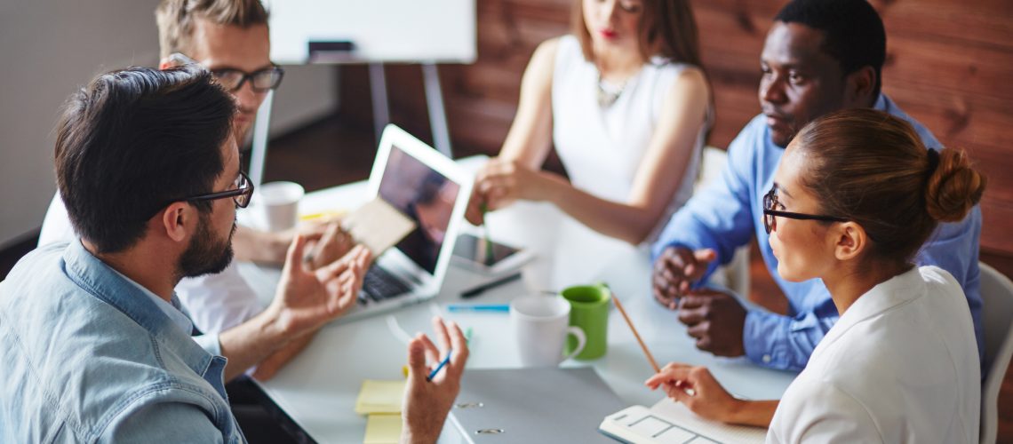 Team members engaged in a meeting around a table, actively discussing and listening to each other, representing strong group dynamics