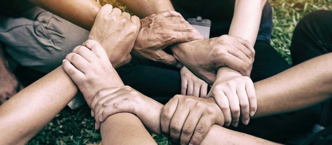 Hands of diverse individuals joining together in unison, symbolizing teamwork, unity, and inclusion.